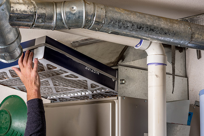 Man replaces a filter in a furnace